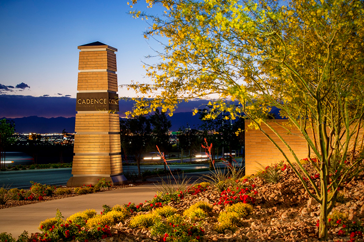 A stone monument with a sign on it by a body of water.