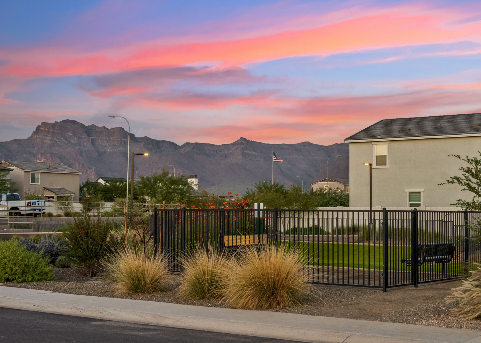 A fenced in area with a building and mountains in the background.
