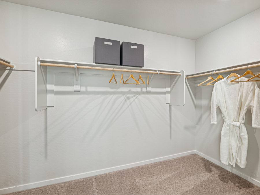 A white shower with a television and clothes on the wall.