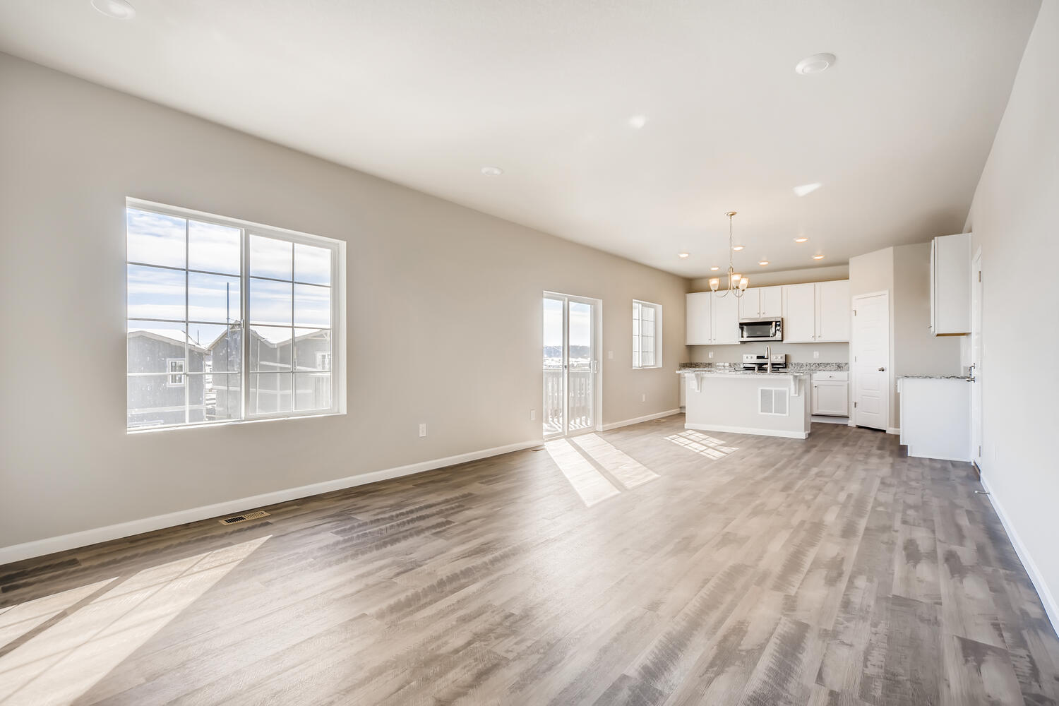 A large empty room with a wood floor and white cabinets.
