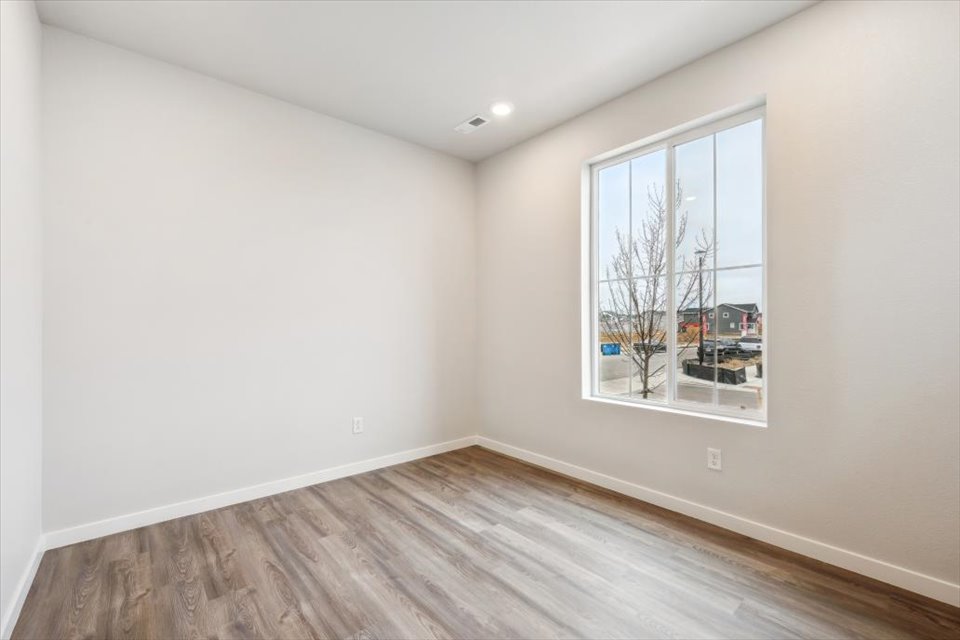 A room with a wood floor and a window with a tree outside.