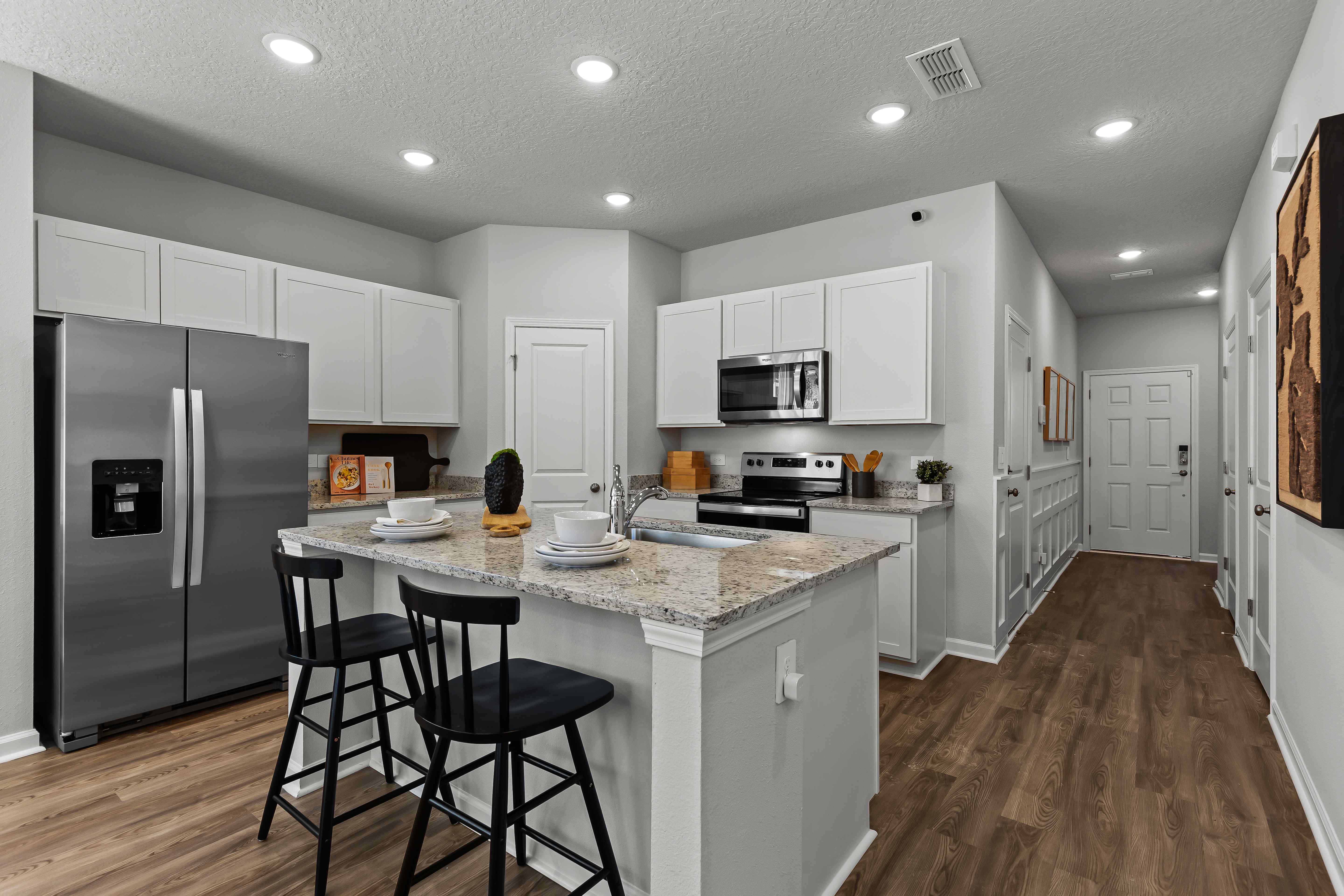 Davor Model Paired Home Kitchen with White Cabinets and Stainless Steel Appliances at The Landings at Pecan Park
