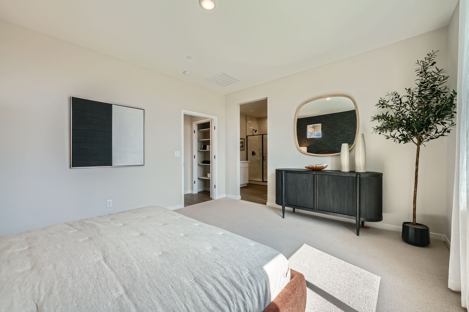 A bedroom with a bed and a plant.
