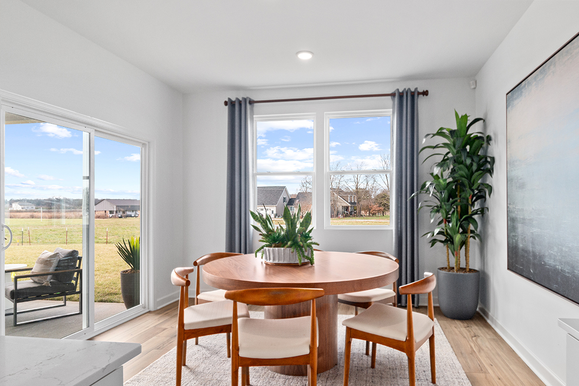 A table and chairs in a room with a window and a view of the water.