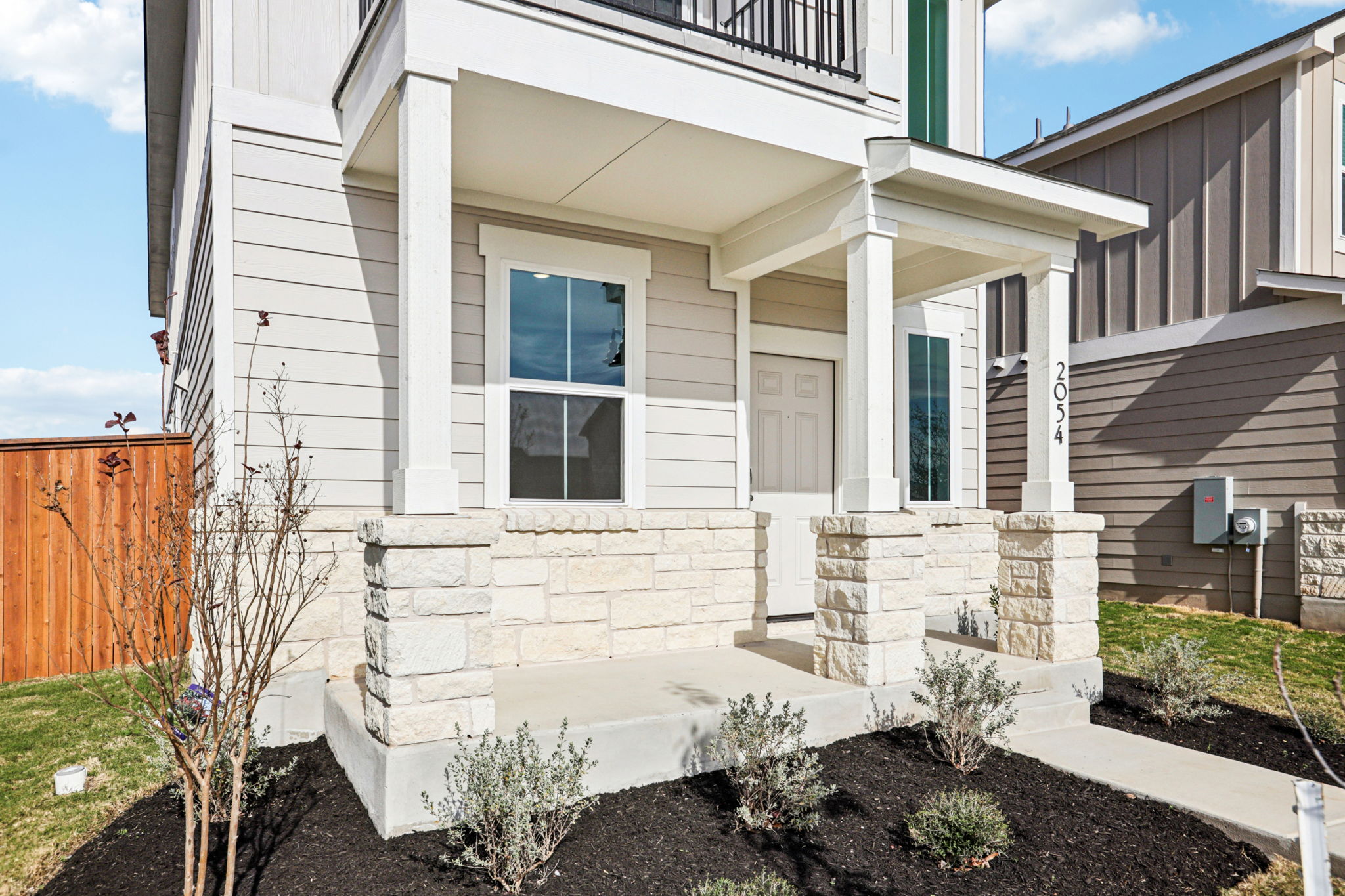 A white house with a stone wall.