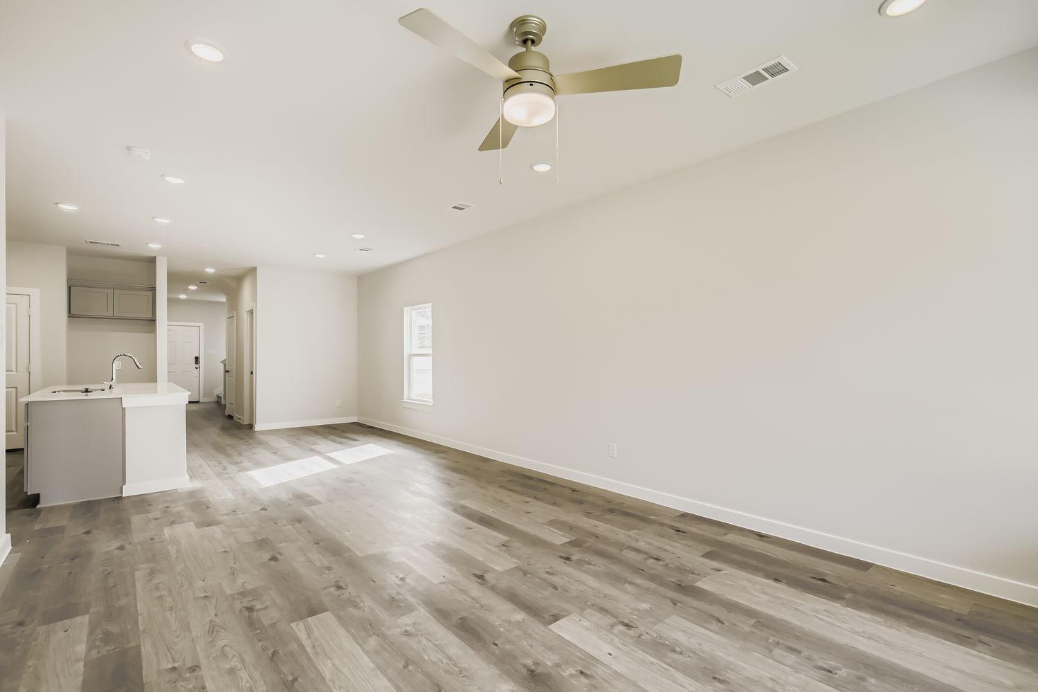 A large empty room with a wood floor and a ceiling fan.