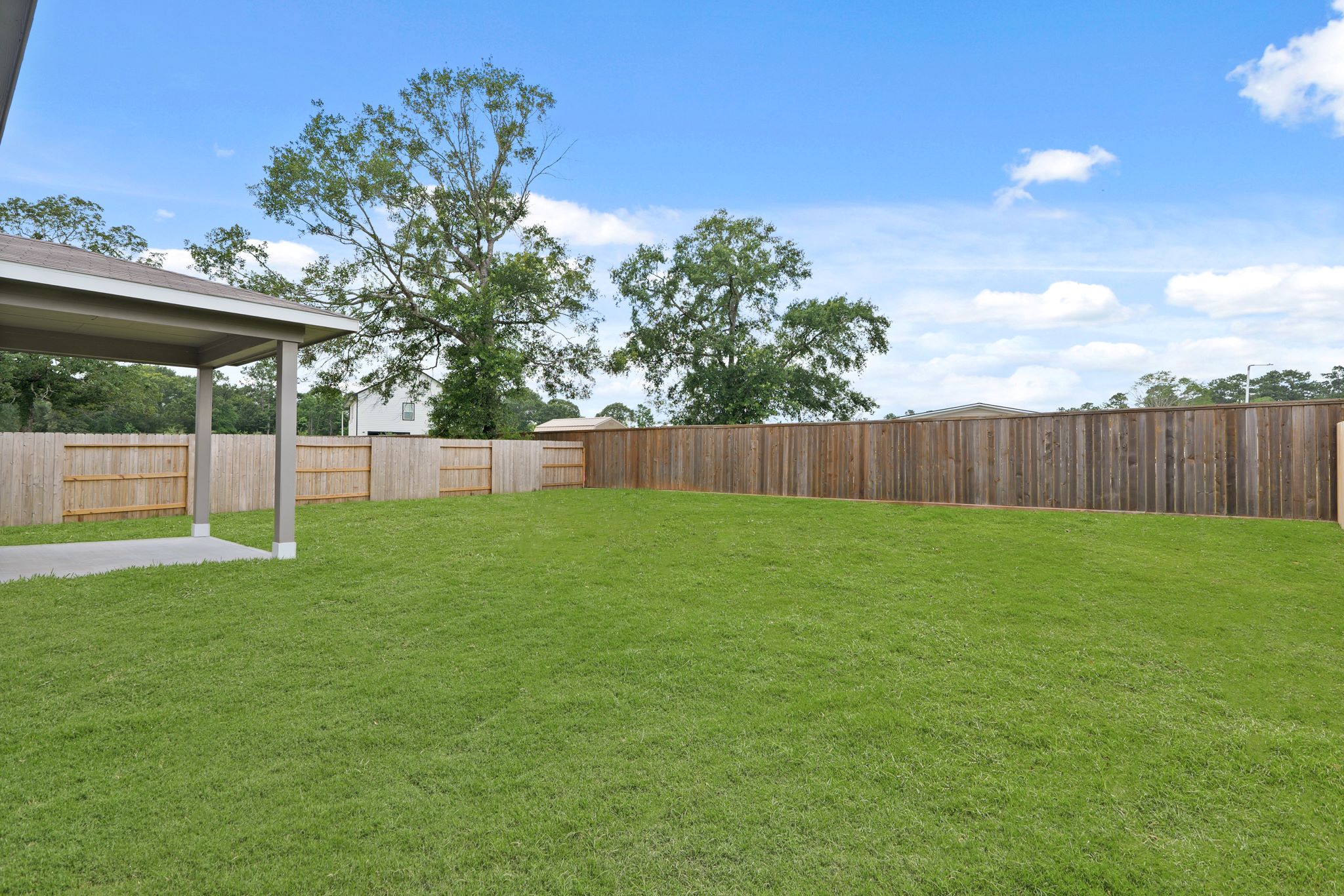 A fenced in yard with a tree and a house in the background.