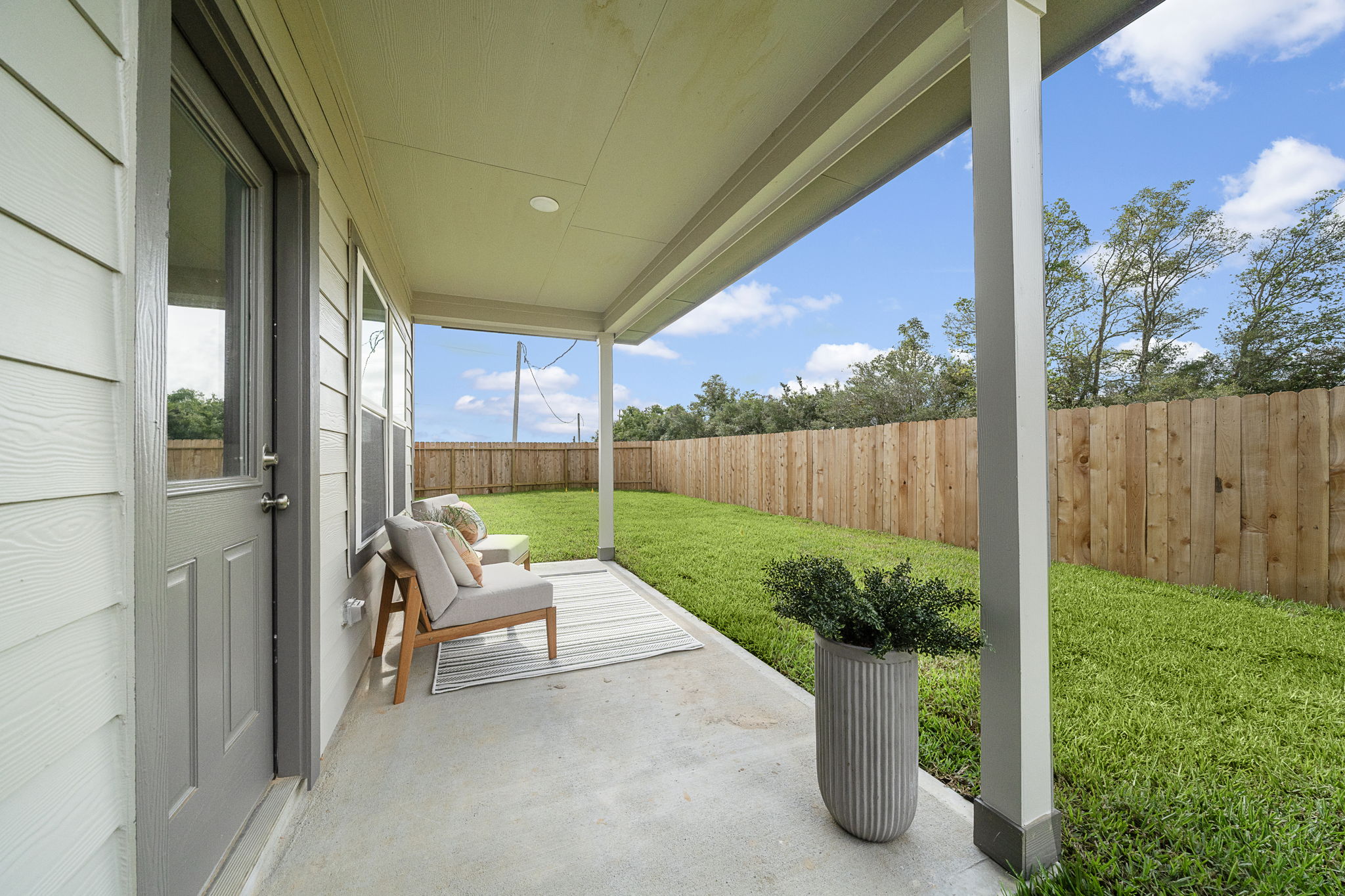 A patio with a chair and a planter and a fence.