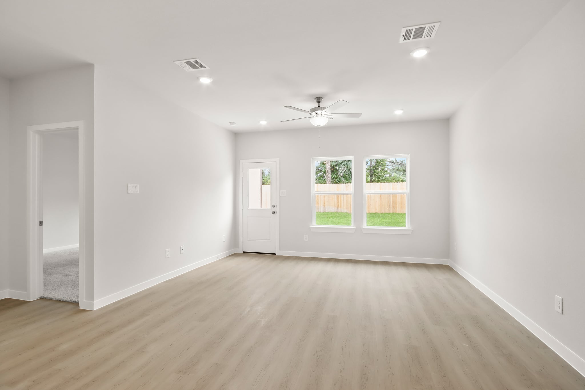A room with a wood floor and a ceiling fan and a wood floor.
