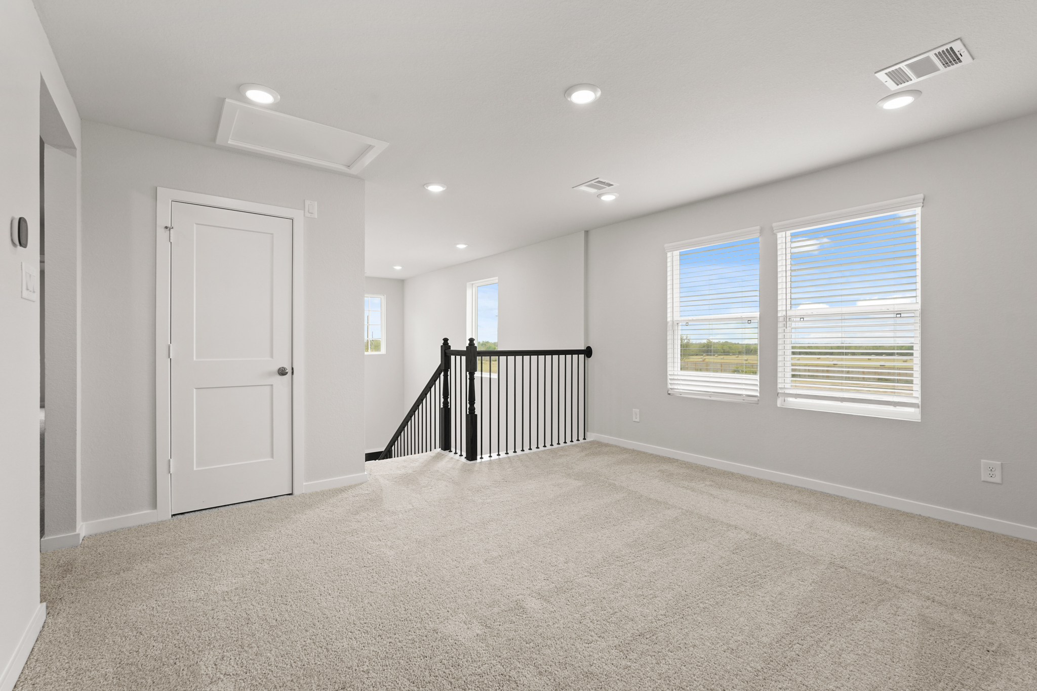 A room with white walls and a black railing.