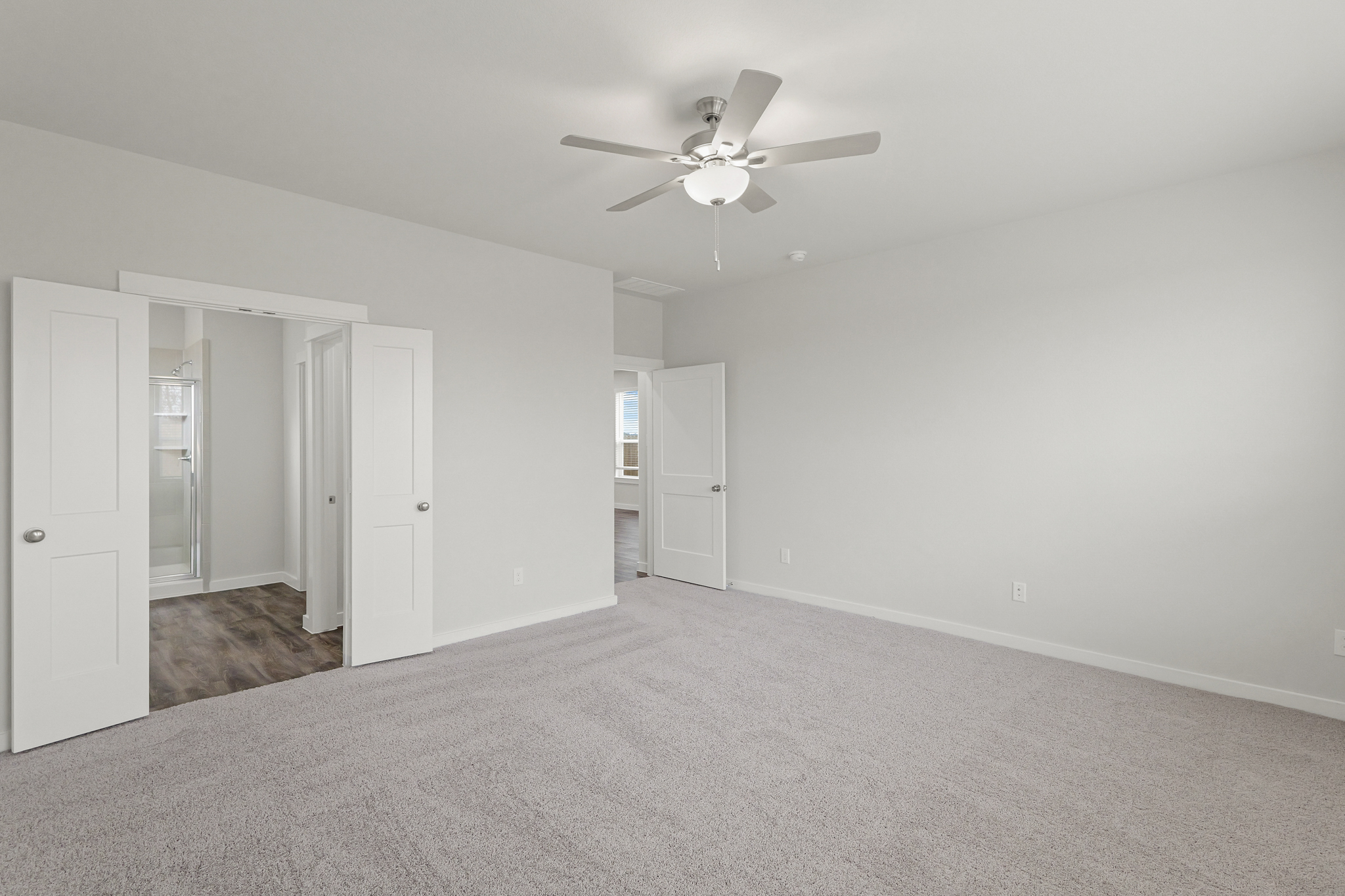 A room with a ceiling fan and white doors.