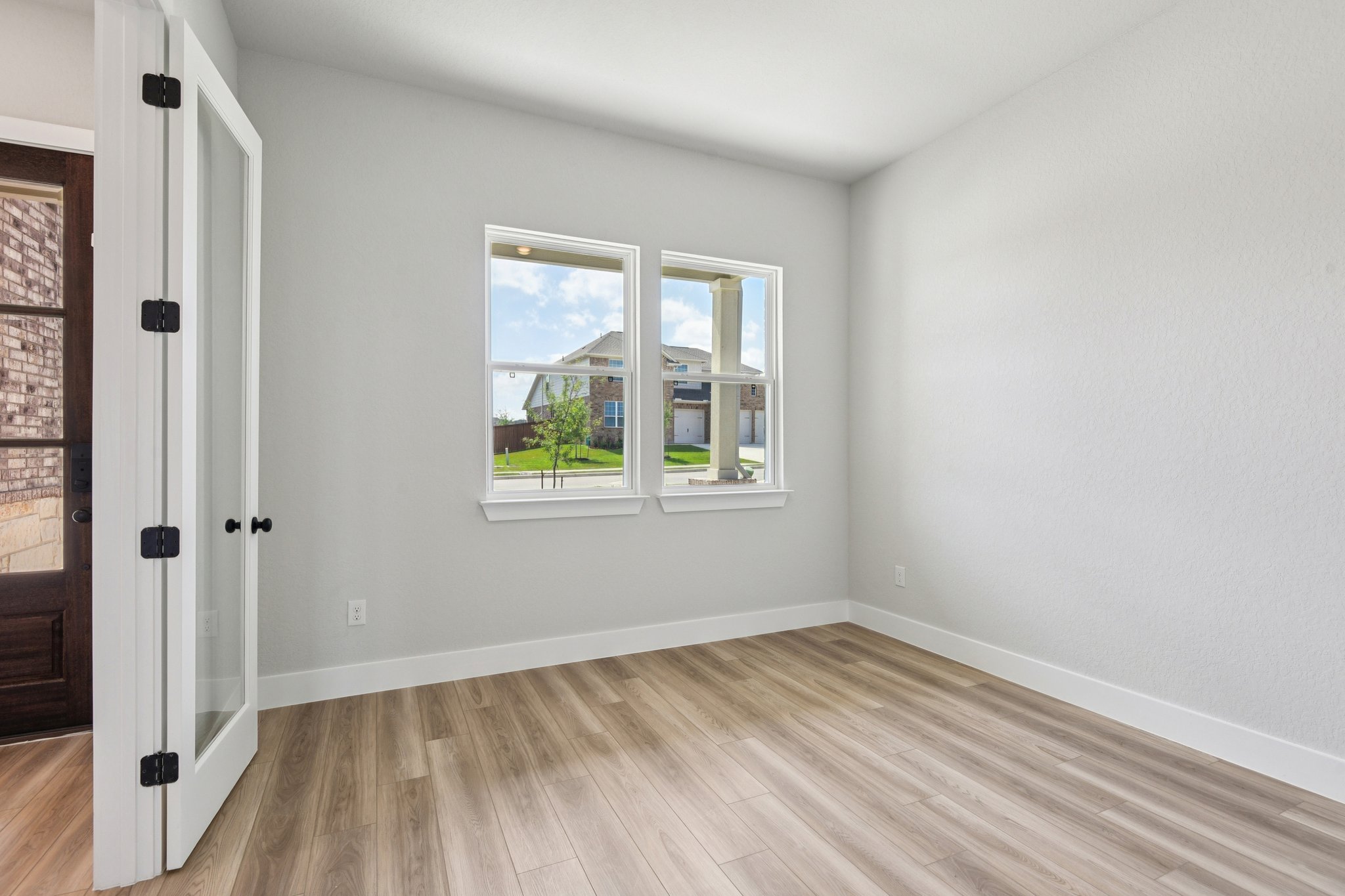 A room with a wood floor and a window with a view of the water.