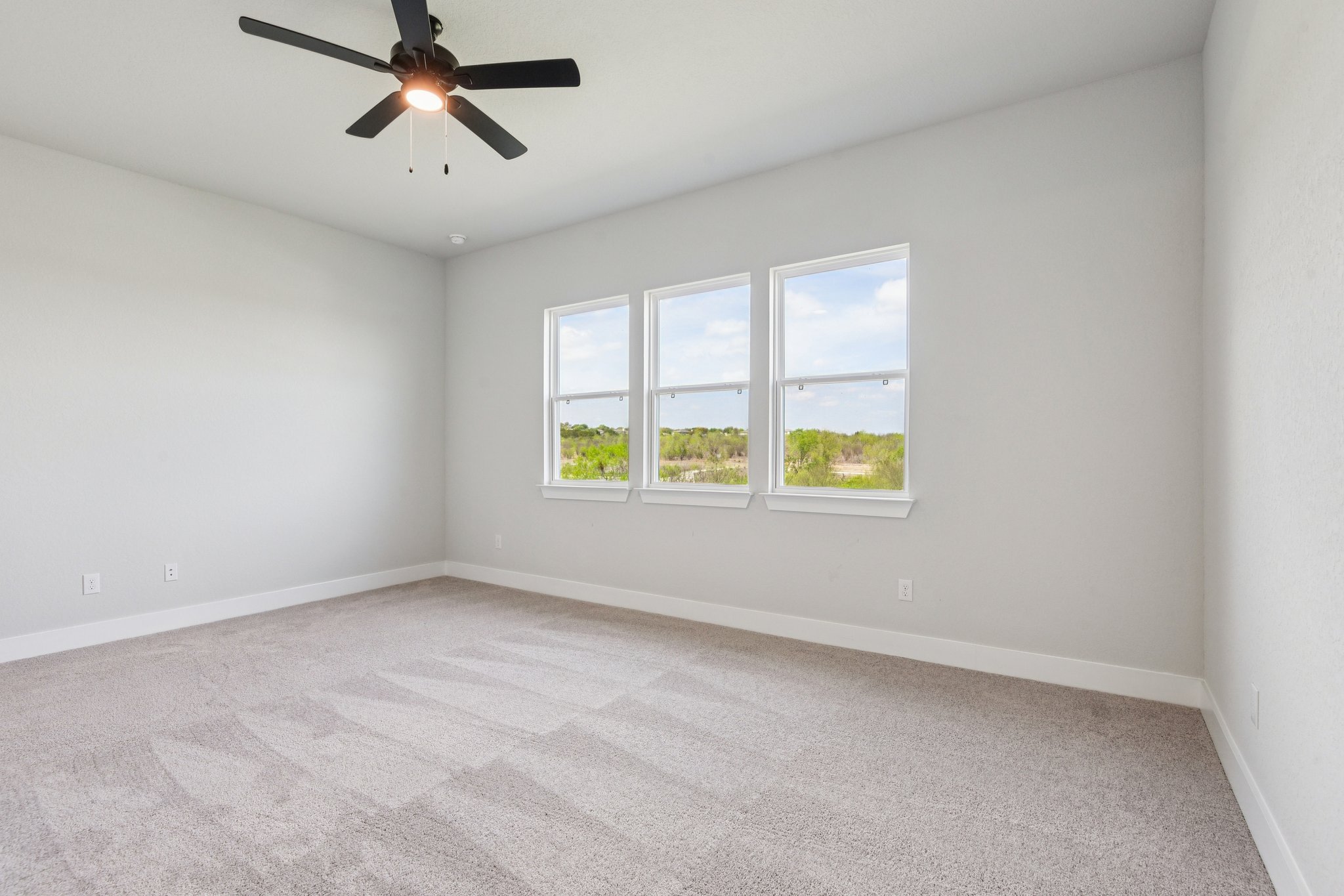 A room with a ceiling fan and a window with a light.