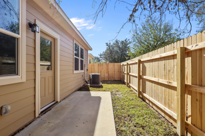 A fenced in yard with a wood gate and a house.