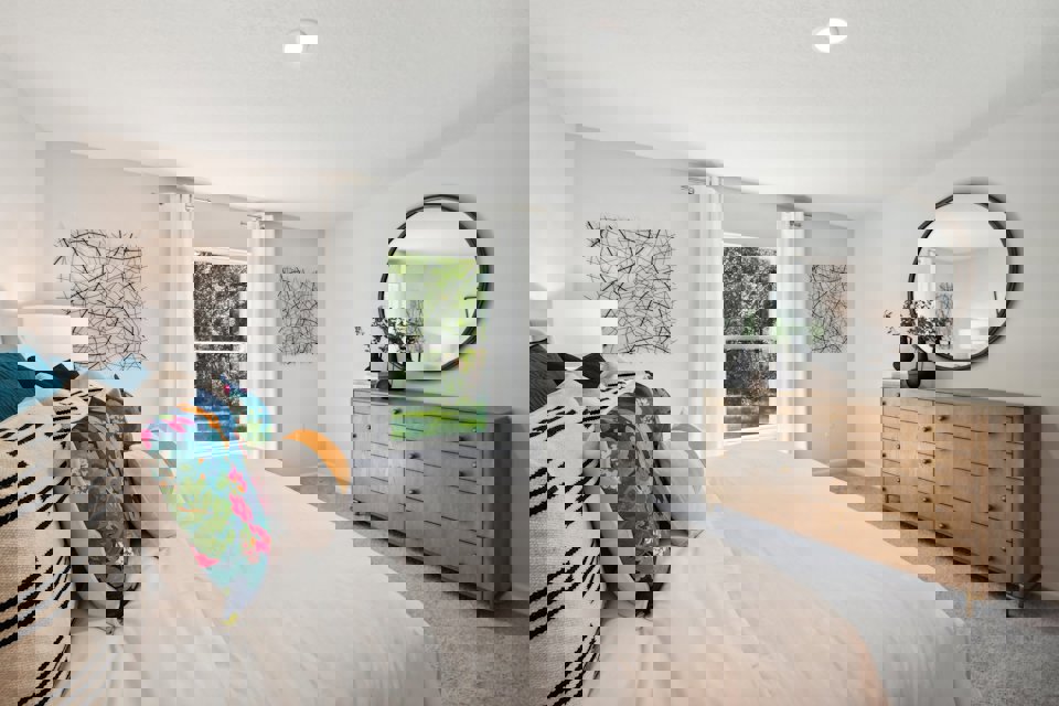 A bedroom with a bed and a mirror.