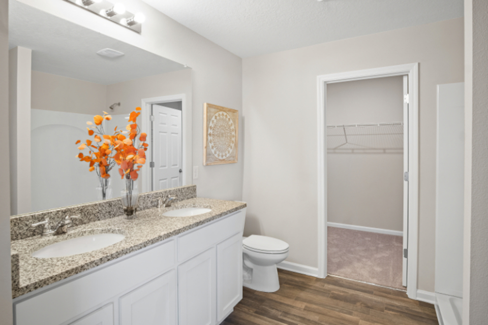 A bathroom with a sink toilet and a flower vase.