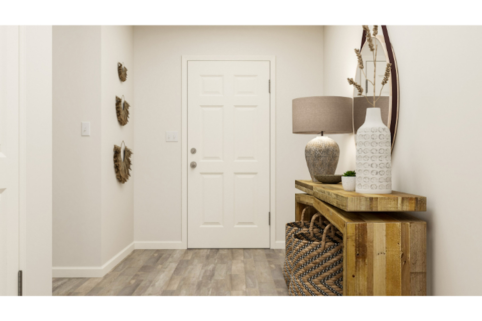 A room with a table and a lamp and a white door.