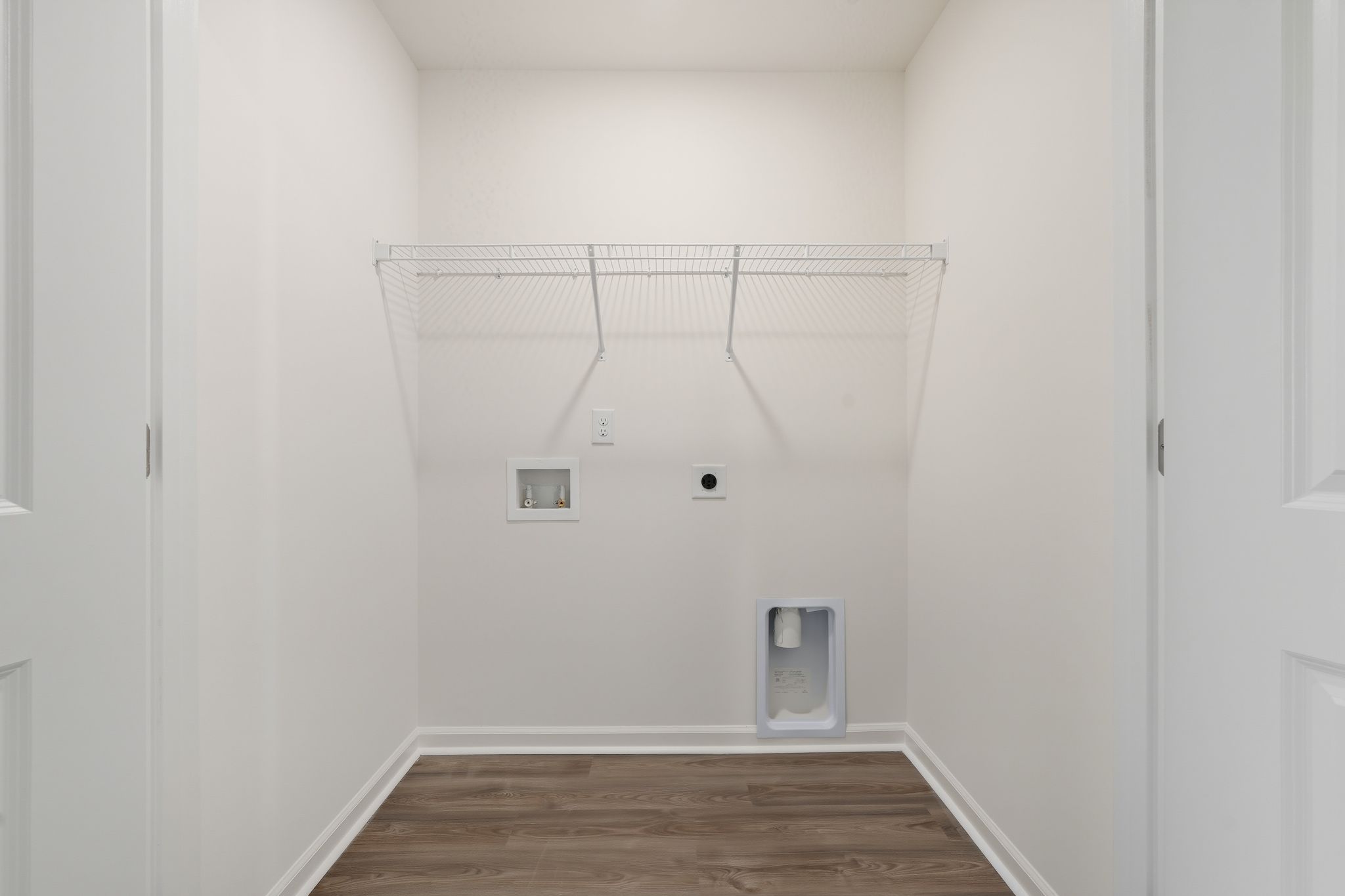 A white room with a wood floor and a metal rack.